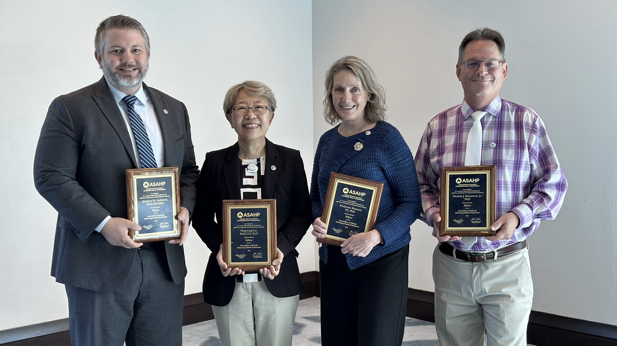 Group photo of four indivduals with plaques